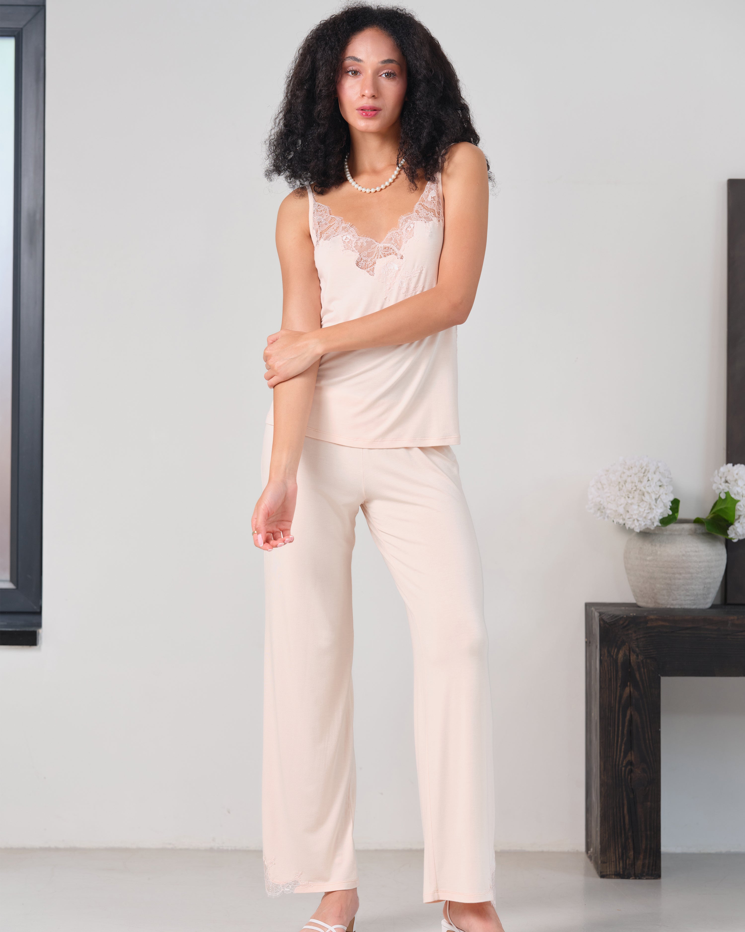 Effetto bamboo camisole pajama set 03163 – women's sleepwear, rosy peach
Woman wearing a light pink lace top and cream pants in a minimalistic room.