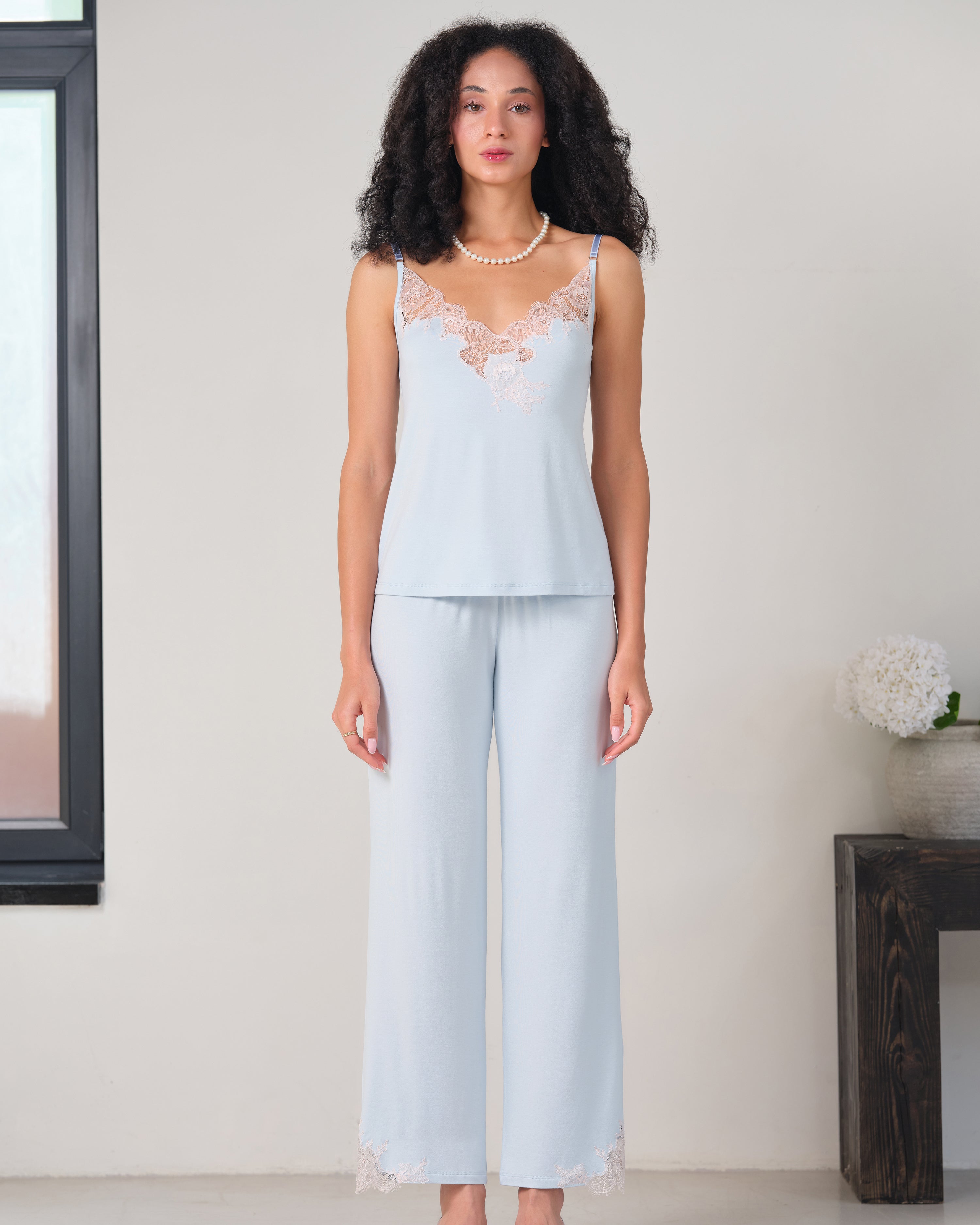Effetto bamboo camisole pajama set 03163 – women's sleepwear, icy blue
Woman wearing a light blue lace top and wide-leg pants in a minimalistic room.